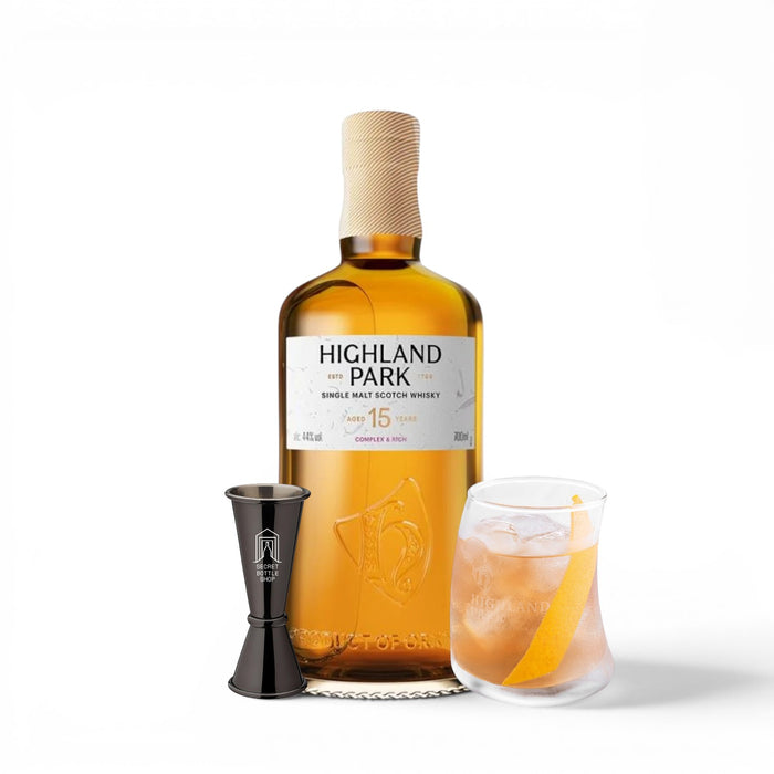Highland Park whisky bottle with a glass of cocktail and jigger on a white background