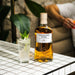 Highland Park whisky bottle with a glass of iced drink on a tiled surface.