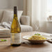 Bottle of Jaffelin Chardonnay wine on a table with a plate of pasta in a cozy indoor setting.