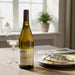 Bottle of Tafelvin Chardonnay with a glass of wine and fish dish on a table.