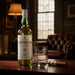 Laphroaig whisky bottle and glass on a wooden surface with a blurred background