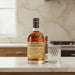 Bottle of Monkey Shoulder whiskey on a kitchen counter with a glass and a cigar.