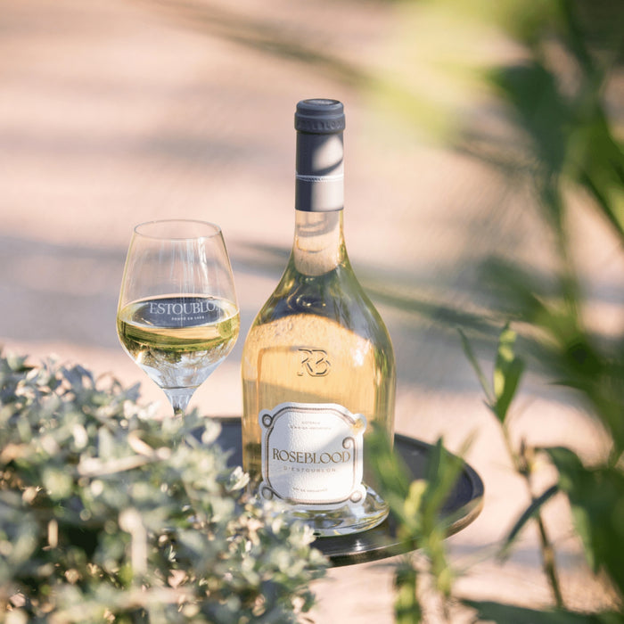 Bottle and glass of white wine with 'Rosewood' label on a blurred natural background