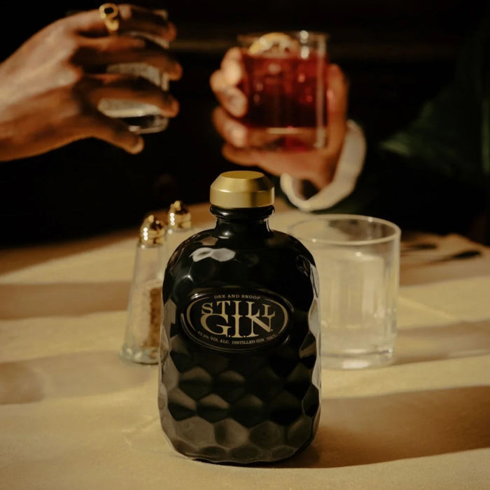 Still G.I.N. Gin By Dr. Dre & Snoop Dogg bottle with two people holding glasses in the background