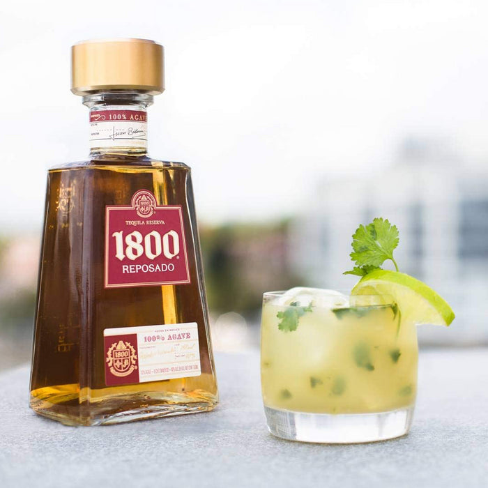 bottle of 1800 reposado tequila reserva with a glass of mojito with lime and mint