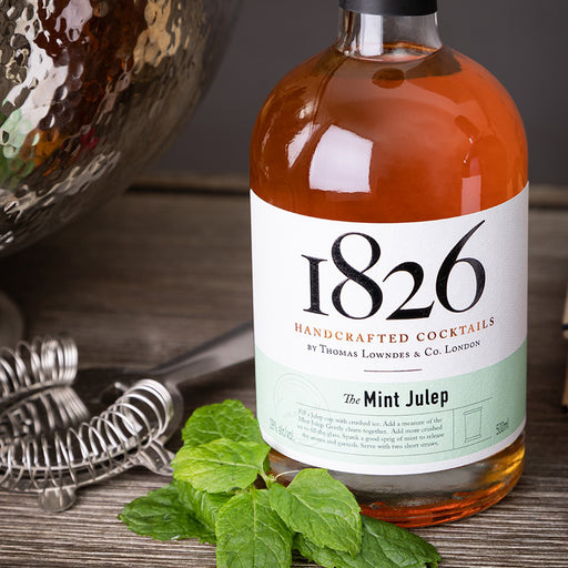 bottle of 1826 mint julep with mint and a cocktail strainer