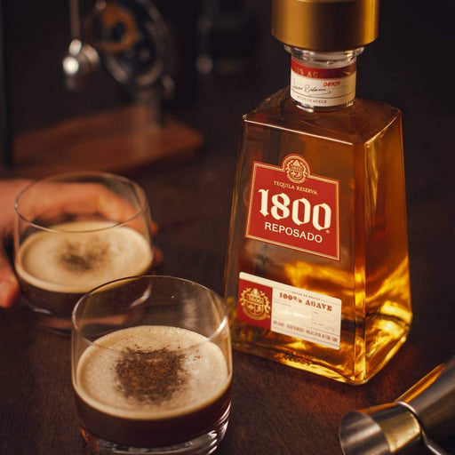 bottle of 1800 reposado tequila reserva with 2 poured glasses