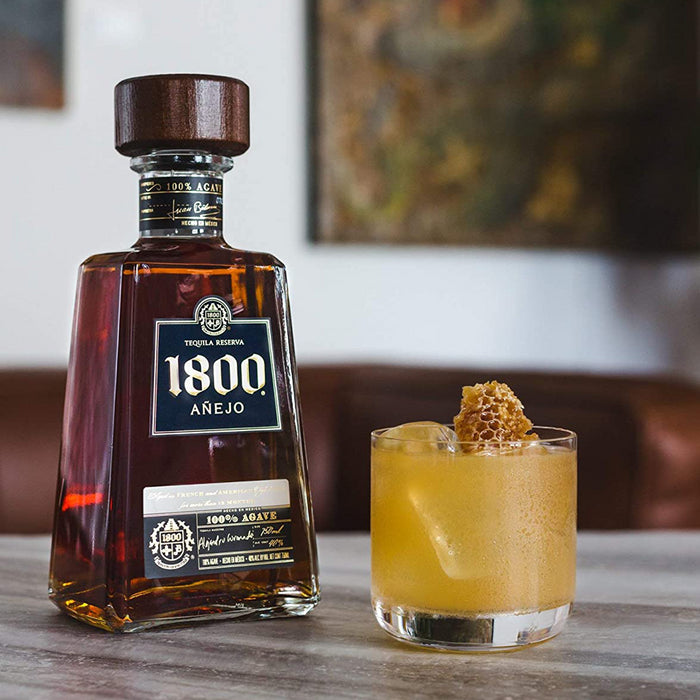 bottle of 1800 anejo tequila reserva and glass with honey comb and ice